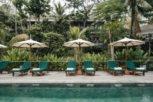 a group of chairs and umbrellas next to a pool at Sanglung Villas & Suites in Kubutambahan