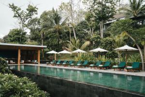 a pool at a resort with chairs and umbrellas at Sanglung Villas & Suites in Kubutambahan