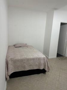 a bedroom with a bed in a white room at KITNET mobiliada com ar condicionado in Guarujá