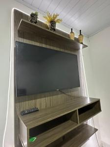 a large flat screen tv on a wooden entertainment center at KITNET mobiliada com ar condicionado in Guarujá