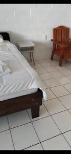 ein Schlafzimmer mit einem Bett und einer Bank auf einem gefliesten Boden in der Unterkunft Uncle Ben's in Apia