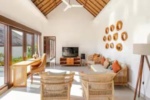 a living room with wicker chairs and a television at Villa Leelavadee in Uluwatu