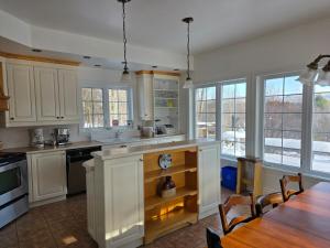 a kitchen with white cabinets and a table and chairs at Domaine des sentiers in Mansonville