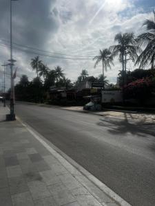 an empty street with palm trees on the side of the road at Homsetay Đồng Phát in Ấp Thiện Phước