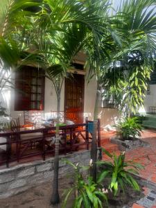 a patio with a table and chairs and palm trees at Homsetay Đồng Phát in Ấp Thiện Phước