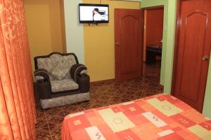 a bedroom with a chair and a tv on a wall at Residencial Norandes in Huaraz