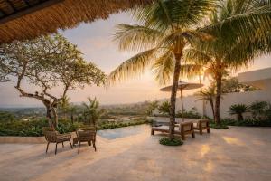 a patio with a table and chairs and palm trees at Balidroomvilla's in Candidasa