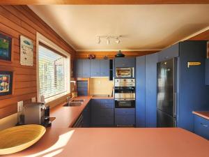 a kitchen with blue cabinets and a counter top at Hahei Beachside Escape in Hahei +21 photos