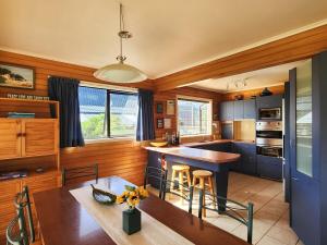 a kitchen with blue cabinets and a table with chairs at Hahei Beachside Escape in Hahei