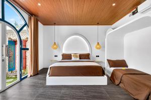 two beds in a bedroom with an arched window at Arch Penida by Bali Cabin in Nusa Penida