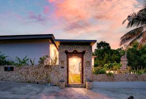 a door to a house with a stone wall at Arch Penida by Bali Cabin in Nusa Penida