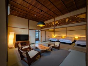 a bedroom with two beds and a flat screen tv at 古民家ラグジュアリーホテル 金井西洋館 in Sado
