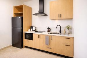 a kitchen with wooden cabinets and a black refrigerator at Guest Space Fiji - Port Denarau Apts in Denarau