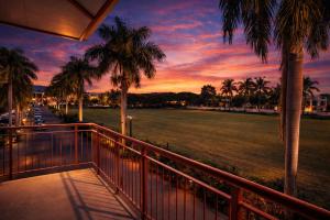 a sunset from a balcony with palm trees and a field at Guest Space Fiji - Port Denarau Apts in Denarau +2 photos