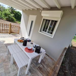 a white table and bench on a patio at Canopée Créole in Petit-Canal