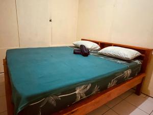 a bed with a green sheet and two pillows at Bunaken Scuba Guest House in Bunaken