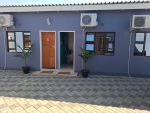 a blue house with two plants in front of it at Cosy Cottage Apartments Block 9 in Francistown