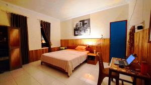 a bedroom with a bed and a desk with a laptop at Tangkoko Macaca in Rinondoran