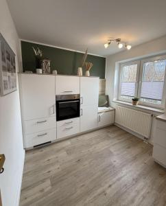 an empty kitchen with white cabinets and a window at Utholmer-Strasse-3 in Brösum
