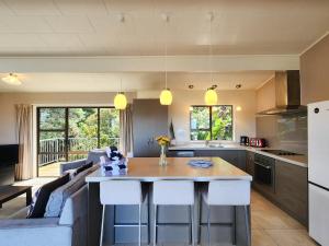 a kitchen and living room with a couch and a table at Cathedral Cove Retreat in Hahei +24 photos
