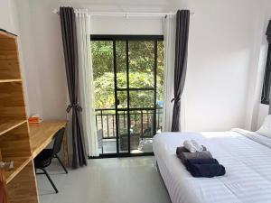 a bedroom with a bed and a desk and a window at Lucky home in the heart of thongsala in Thong Sala