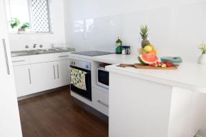 a kitchen with white cabinets and a counter with fruit on it at 1-45 Beech Street in Evans Head +10 photos