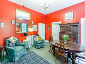 a dining room with orange walls and a table and chairs at The Ivy Wing in Slickly