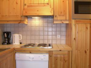 La cuisine est équipée de placards en bois et d'un four avec plaques de cuisson. dans l'établissement Stylish Apartment in M ribel with Balcony, à Méribel