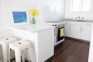 a white kitchen with white cabinets and white stools at 2-45 Beech Street in Evans Head +8 photos