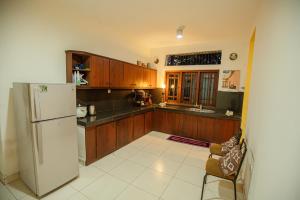 a kitchen with wooden cabinets and a white refrigerator at Airport Serenity Villa - Near Colombo Airport in Katunayaka