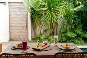 a wooden table with plates of food and drinks on it at Kai Villas Lombok in Kuta Lombok +5 photos