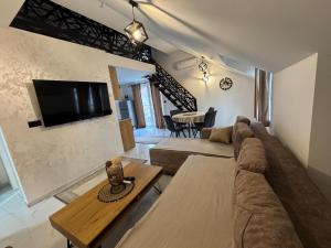 a living room with a couch and a tv on a wall at Apartment Star 2 Ledine in Beograd