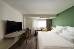 a hotel room with a bed and a flat screen tv at The Akyra Bangkok 11 in Bangkok