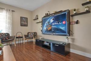 a living room with a flat screen tv on a wall at Galaxy Quest by OC Adventure Homes in Garden Grove