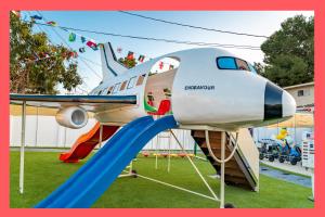 an airplane on a playground with a slide at Galaxy Quest by OC Adventure Homes in Garden Grove