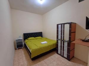 a bedroom with a bed with a green bedspread at Irma Guest House Syariah in Temenggungan