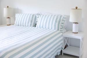 a bed with blue and white striped sheets and lamps at 3-45 Beech Street in Evans Head