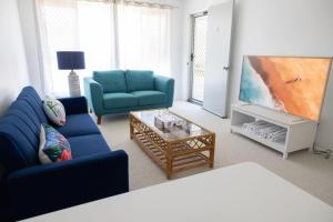 a living room with a blue couch and a tv at 3-45 Beech Street in Evans Head