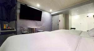 a bedroom with a white bed and a flat screen tv at ZaZaHOTEL in Sosa