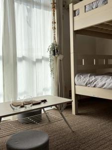 ein Schlafzimmer mit einem Etagenbett und einem Tisch mit zwei Gläsern in der Unterkunft Hanazono501 in Niigata