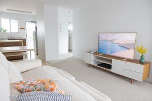 a living room with a white couch and a flat screen tv at 4-45 Beech Street in Evans Head