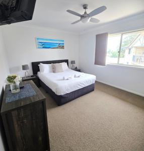 a bedroom with a bed and a ceiling fan at Sandy Toes in Bellara