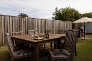 a wooden table with two chairs and a bottle of wine at 4-45 Beech Street in Evans Head +8 photos