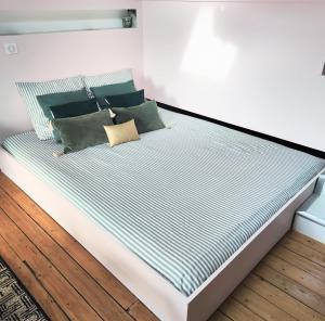 a bed with blue and white striped sheets and pillows at Charmant cocon sous les toits de Bordeaux in Bordeaux