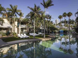 a resort pool with palm trees and white lounge chairs at BreakFree Diamond Beach in Gold Coast