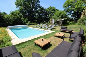 a backyard with a pool with chairs and a table at Petite gare aux oiseaux in Le Châtenet
