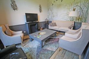 a living room with a couch and chairs and a table at Petite gare aux oiseaux in Le Châtenet