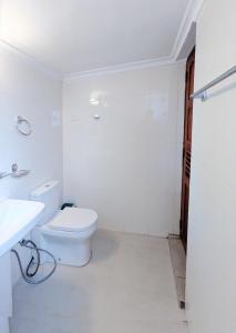 a white bathroom with a toilet and a sink at Hill Crest Mansion in Kandy