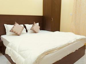 a bed with white sheets and pillows in a room at Hotel Ramkrishna Stay in Khajurāho +5 photos