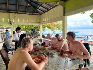 a group of men sitting at a table eating food at Bunaken Scuba Guest House in Bunaken